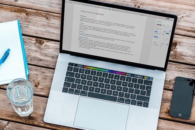 ноутбук laptop on a table next to a glass of water, notebook, and phone